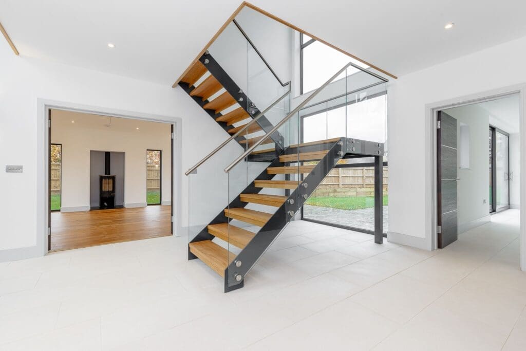 Modern interior featuring a wooden and glass staircase at Southmoor, showcasing luxury timber frame homes in Oxfordshire.