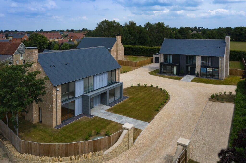 Architectural CGI of two modern brick houses across a gravel driveway at Southmoor, showing luxury timber frame homes.