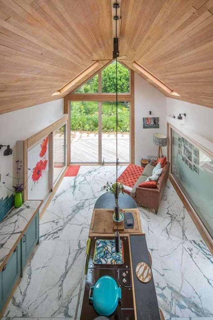 Bright modern living room at Waterfall Lodge with slanted wooden ceiling and large windows, a bespoke timber home by Modh Design.