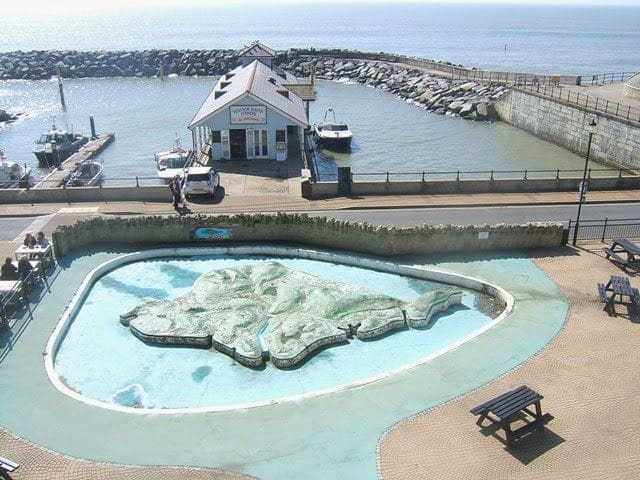 Aerial view of Ventnor Haven Fishery with a miniature Isle of Wight, highlighting coastal timber frame durability.